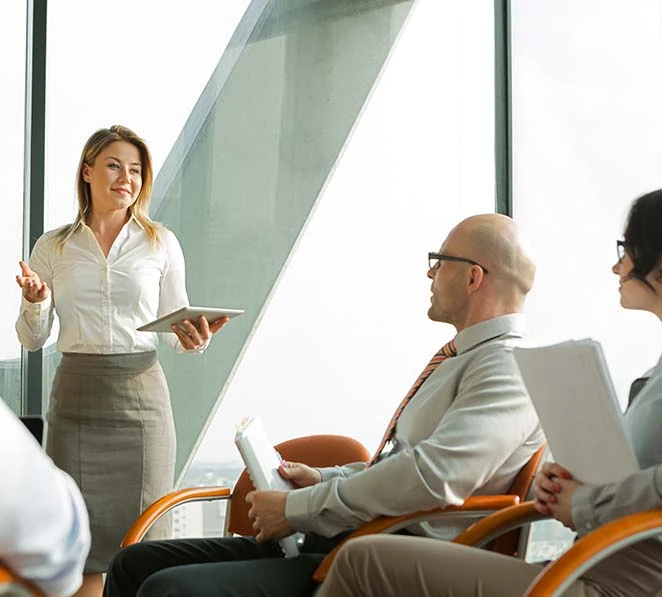 Professional woman in office attire teaching Change Management Courses Australia to a seated colleague during a training session